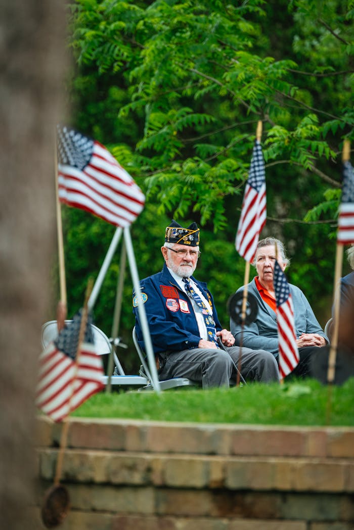why-choose-us Elderly veterans sitting among American flags at an outdoor ceremony.