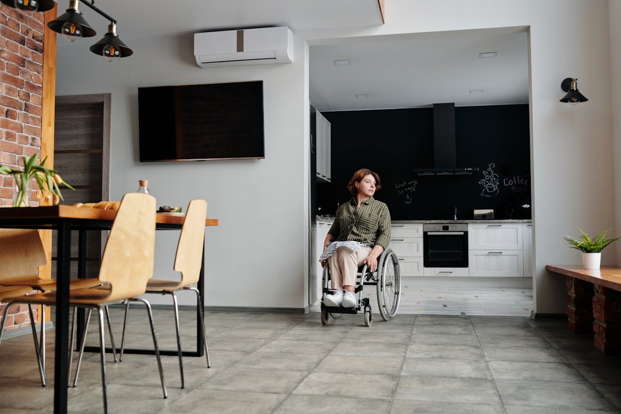 Woman in wheelchair in a modern kitchen setting, deeply contemplating life. Indoor scene highlighting accessibility and inclusion.