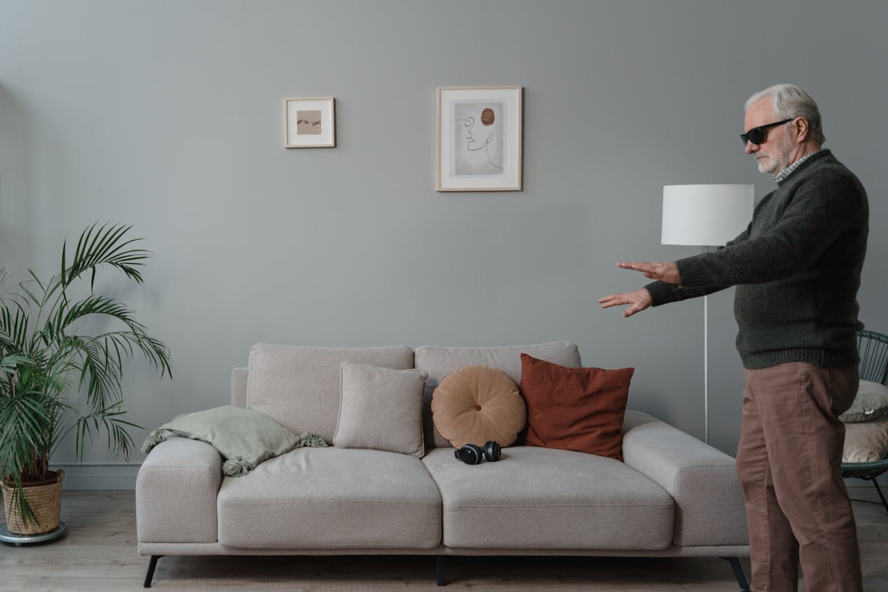 Elderly man with sunglasses navigating living room, illustrating mobility and independence.